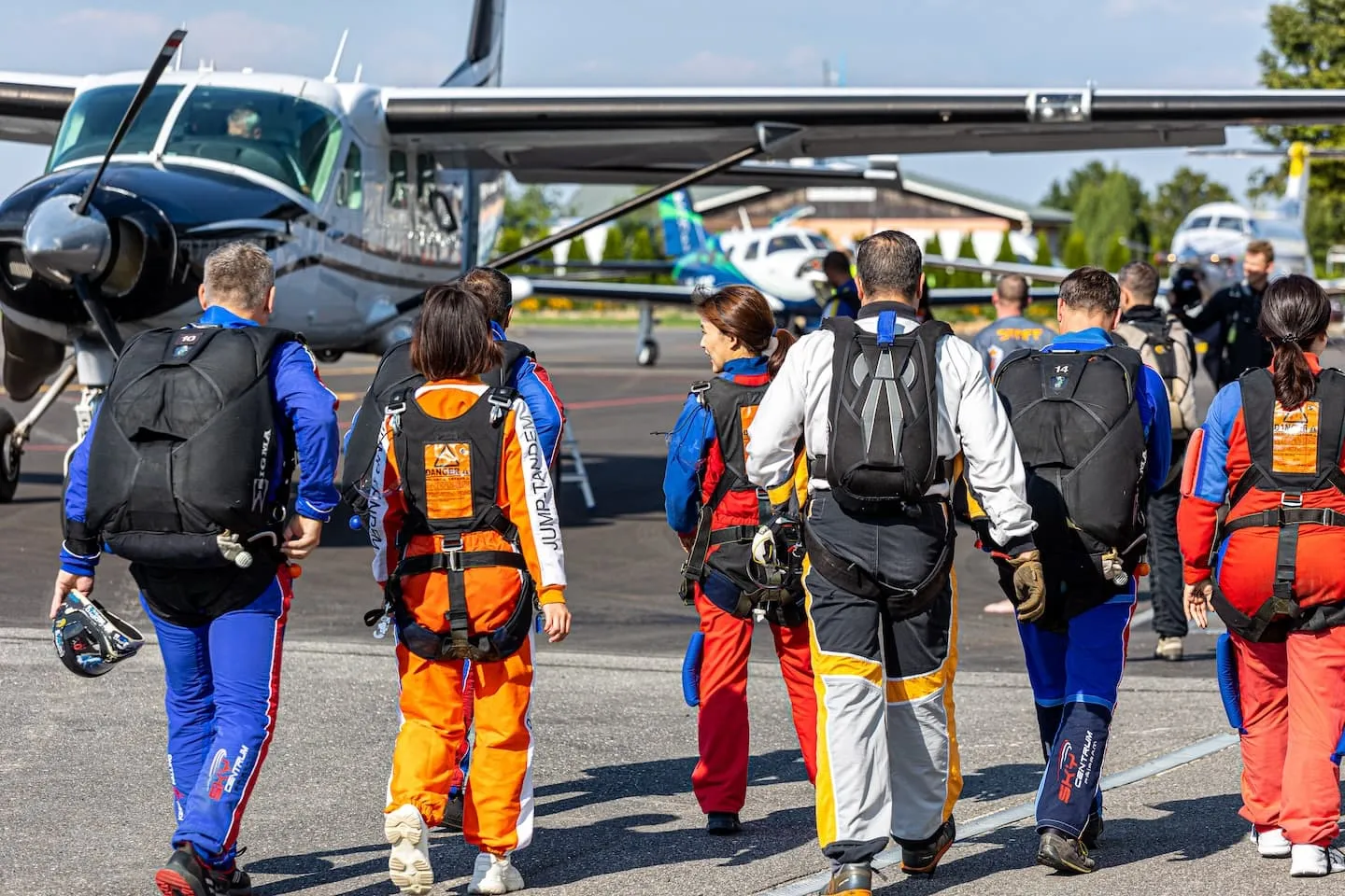 Tandem piloti a pasažéři před nástupem do letadla